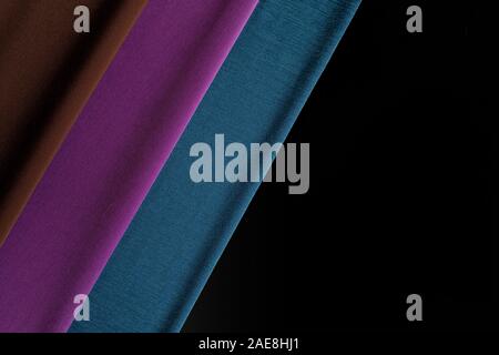 Lavorate a maglia multi-colore di sciarpe close up su uno sfondo nero. Strisce di tessuto. Foto Stock