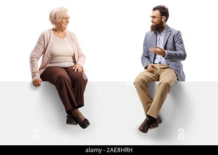 Senior donna e un uomo barbuto seduto su un pannello e parlando isolati su sfondo bianco Foto Stock