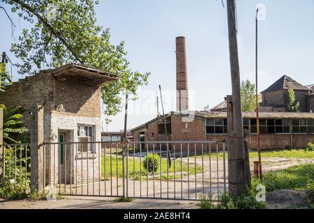 Ingresso di una fabbrica abbandonata e il magazzino con il suo distintivo chimnet mattoni in Europa Orientale, in Pancevo, Serbia, Ex Jugoslavia, durante una s Foto Stock