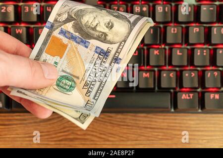 Mano maschio prende i soldi dalla tastiera come un concetto di fare soldi su Internet Foto Stock