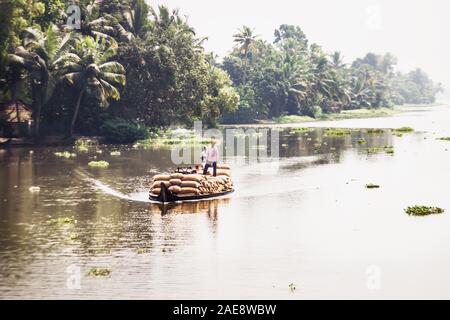 Thottappally, Kerala, India - 17 Novembre 2017: indiano la gente del luogo in una barca riempita con sacchi sul fiume in lungo il Quilon kottapuram per via navigabile nel Keral Foto Stock