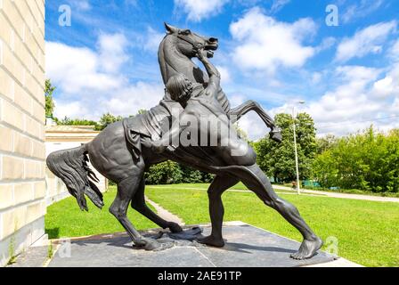 Mosca, Russia, Kuzminki Park - Luglio 10, 2019: scultura domatore di cavalli da Peter Klodt accanto alla costruzione del cantiere stabile con un padiglione musicale su Foto Stock