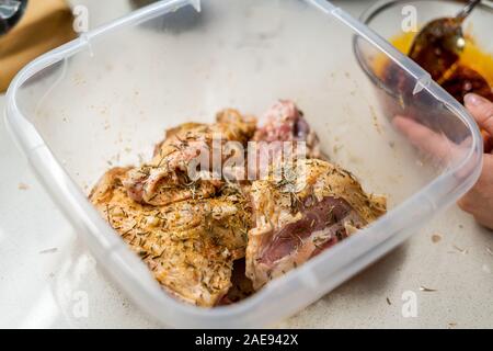 Crudo marinato le cosce di pollo con la salsa di pomodoro, cipolla, rosmarino e patate pronto a cuocere in forno. Alimenti biologici. Foto Stock