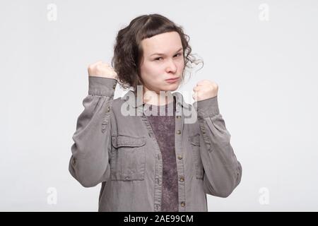 Donna forte con grave aspetto fiducioso mantenendo i pugni rinserrata di fronte a lei per difendere se stessa. La difesa e il concetto di protezione. Studio shot Foto Stock