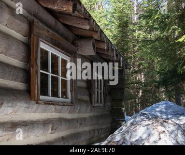 Pareti e finestre di log cabin in una foresta con ghiaccioli in Canada. Foto Stock
