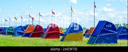 Fila di colorati strandkorbs con cappuccio sedie da spiaggia accanto al fiume Elba Ottendorf Lido Cuxhaven bassa Sassonia Germania. Foto Stock