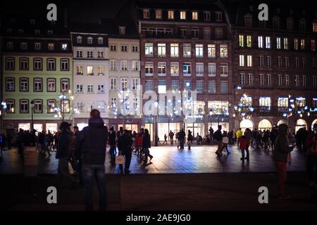 Strasburgo, Francia - Dic 20, 2016: sagome di persone alla scoperta della città di Strasburgo di notte con edifici molto alti e le decorazioni di Natale nel corso annuale di Marche de Noel mercato iconica Foto Stock