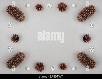 Bordo di Natale con argento fiocchi di neve e coni fir su sfondo grigio. Felice Anno Nuovo. Concetto di inverno. Spazio per il testo. Vista superiore, piatto laici. Foto Stock