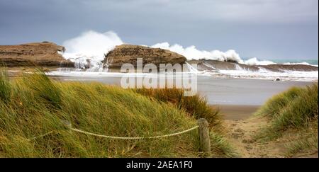 Funi a proteggere le dune di sabbia e guida il cammino per il sentiero che conduce alla spiaggia e reef su un vento tempestoso giorno con massicce ondate Foto Stock