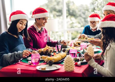 Ritratto di felice grande Famiglia celebra santa cappelli divertendosi e pranzo insieme godendo di trascorrere del tempo insieme nel tempo di Natale a casa Foto Stock