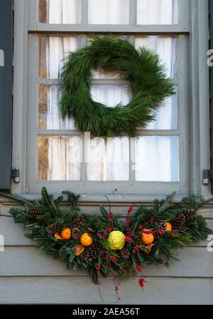 Natale evergreen swag decorata con arance, pigne nelle quali, bacche rosse e una centrale di osage orange. Al di sopra è una pianura verde ghirlanda. Colonial Williamsburg. Foto Stock