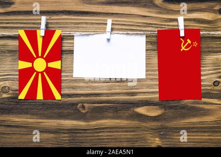 Appendere bandiere di Macedonia e Unione Sovietica attaccata alla corda con vestiti perni con copia spazio bianco sulla nota carta su sfondo di legno.Diplomatic rel Foto Stock