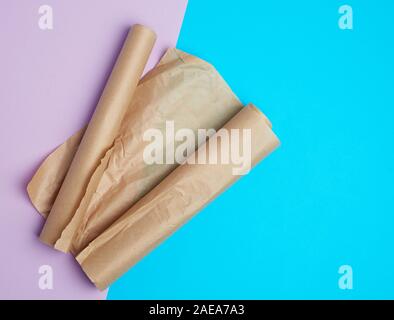 Due rotoli laminati di pergamena marrone carta da forno su uno sfondo colorato, vista dall'alto, posto per pasta Foto Stock