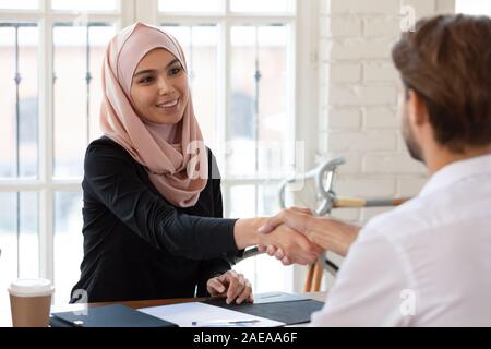 Sorridente femmina arabo hr manager stringono le mani con job ricorrente. Foto Stock