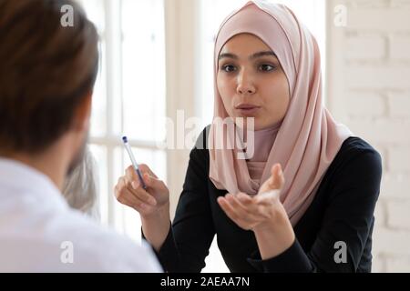 Giovane imprenditrice araba hijab come parlare di sesso maschile di team leader. Foto Stock