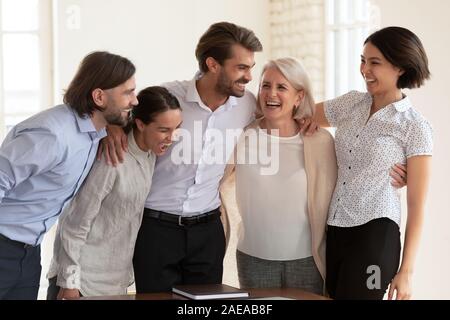 Overjoyed razza mista giovani e vecchi colleghi per celebrare il successo. Foto Stock