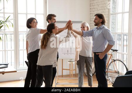 Overjoyed centro anziani e giovani colleghi multirazziale dando alta 5. Foto Stock