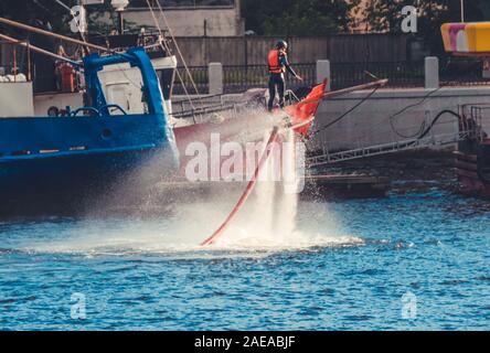 Giovane donna sulla scheda di volare oltre il fiume Neva nei pressi del porto Foto Stock