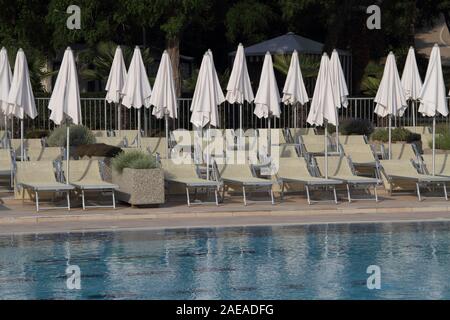 Lettini ed ombrelloni in piscina Foto Stock