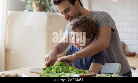 In cucina domestica padre insegna poco figlio come insalata di cook Foto Stock