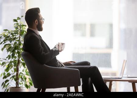 Imprenditore arabo guarda nella distanza prendendo break in ufficio Foto Stock