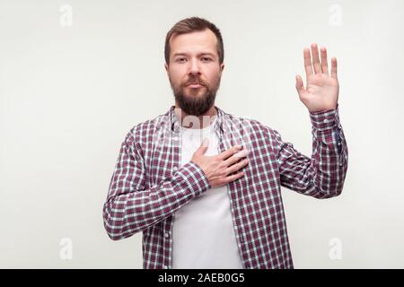 Lo giuro! Ritratto di responsabile uomo barbuto in plaid shirt mantenendo la mano sul petto rendendo promessa, il giuramento di dire la verità, essere onesto dedicato. ind Foto Stock