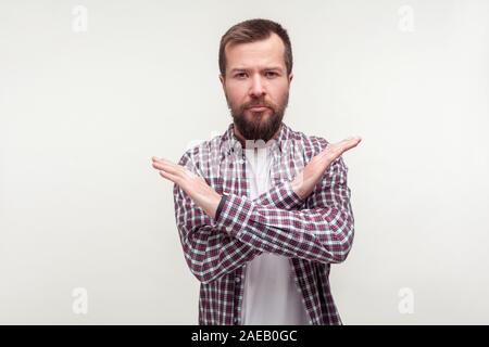 Nessun modo! Ritratto di determinato uomo barbuto in casuale plaid shirt attraversando le mani e cercando rabbiosamente in telecamera, il significato di questo è il fine corsa, avvertimento g Foto Stock