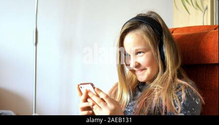 La ragazza usa la tecnologia moderna. Bambina che gioca sul cellulare. Il bambino trascorre il suo tempo libero con la tecnologia moderna. Foto Stock