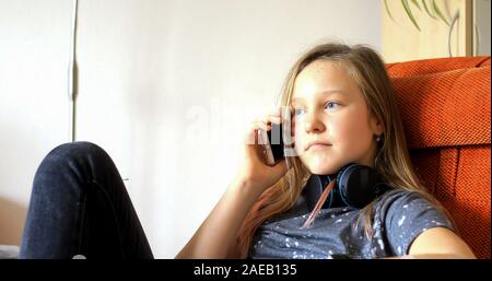 La ragazza usa la tecnologia moderna. Bambina che gioca sul cellulare. Il bambino trascorre il suo tempo libero con la tecnologia moderna. Foto Stock