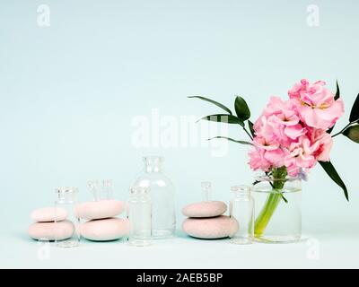 Fiori rosa in vaso, accanto alle pietre Zen, tubi di olii, il tema della Spa e relax Foto Stock