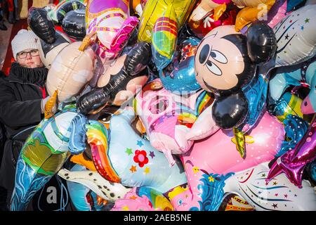 London, Regno Unito - 25 novembre 2019 - Un personale femminile vendita palloncini flottante in Natale luna park, Winter Wonderland Foto Stock