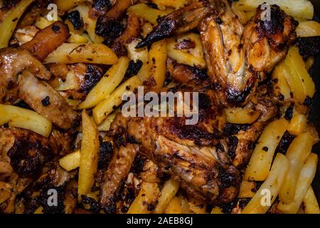 Ali di pollo marinato con spezie fritto in padella con patate. Cucina casalinga. Foto Stock