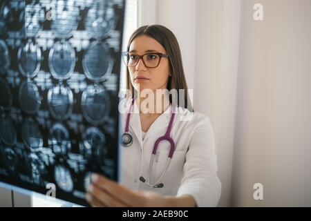 Giovani donne medico guardando MRI scan Foto Stock
