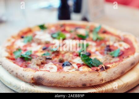 Pizza con carne e puttanesca, close-up, la messa a fuoco sulla crosta, tonica immagine Foto Stock