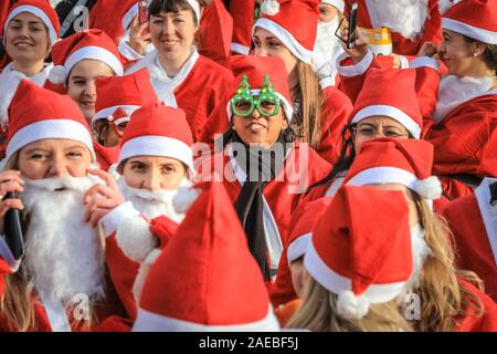 Brockwell Park, Londra, Regno Unito, 08 dic 2019. I Babbi Natale hanno un warm up prima della gara. Attorno al 3000 Santa corridori vestiti da Babbo Natale partecipa all'annuale London Santa Dash 2019. Questo anno il 5k e 10k i percorsi per i corridori di tutte le età conduce attraverso Brockwell Park, Londra del sud. La Santa Dash alza il prezzo per dare bambini gravemente ammalati presso il Great Ormond Street Hospital (Gosh) la possibilità di un futuro migliore. Foto Stock