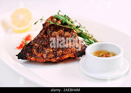 Grigliata di passera pianuzza (sogliola pesce) con limone, erbe e salsa saporita, tonica immagine Foto Stock