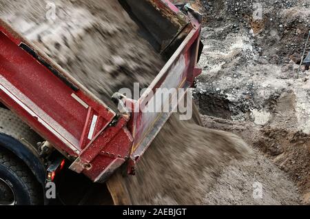 Un camion scarica un carico di sabbia su un sito in costruzione Foto Stock