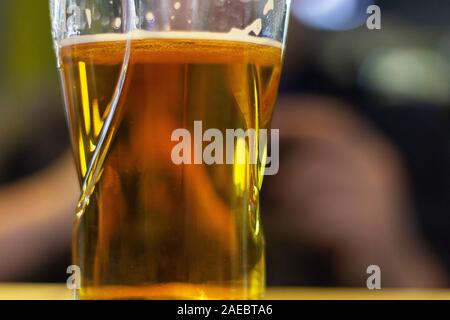 Un bicchiere di birra al bar. persone in background alla ricerca telefono Foto Stock