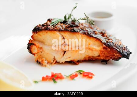 La Passera pianuzza grigliate bistecca con limone e salsa appetitosa sulla piastra bianca, tonica immagine Foto Stock