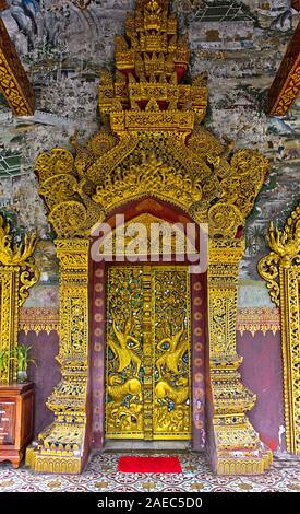 Boscoso dorato dei pannelli della porta in bassorilievi raffiguranti limitatrice Rama combattimenti mitico leoni, tempio Wat Pa Phai, Luang Prabang, Laos Foto Stock