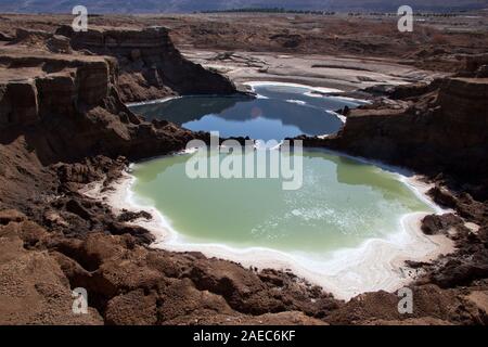 Vista dei fori di pozzo sulla riva del Mar Morto, Israele. I fori di pozzo sono causati dal rapido calo del livello dell'acqua (ca. 5 cm al mese) Foto Stock