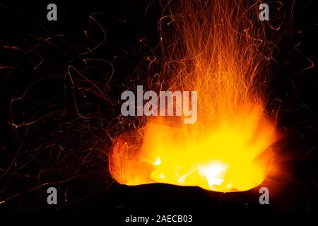 Scintille di carbone che brucia la diffusione su sfondo scuro. Foto Stock