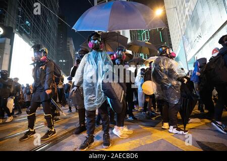 I manifestanti che indossano maschere antigas per proteggere dalla polizia gas lacrimogeni durante la dimostrazione.centinaia di migliaia di persone hanno marciato attraverso Hong Kong per contrassegnare la Giornata dei Diritti Umani e premere per una maggiore democrazia in città. Foto Stock