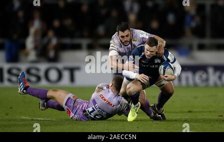 Vendita squali' Chris Ashton è affrontato da Exeter Chiefs' Joe Simmonds (sinistra) e Dave Dennis (destra), durante la Heineken European Champions Cup girone due corrispondono all'AJ Bell Stadium, la vendita. Foto Stock