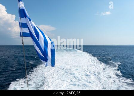 Bandiera Greca e Sentiero dell'acqua la formazione di schiuma dietro un traghetto nel Mare Egeo. La Grecia. Foto Stock