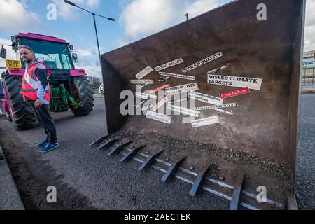 Londra, Regno Unito. 8 dicembre 2019. Estinzione Rebellionhad ha portato un bulldozer per tenere una bugia-in segno di protesta contro l'espansione airport sulla rotatoria di Heathrow riecheggiando Boris Johnson ha promesso sdraiarsi con John McDonnell " di fronte a quelle bulldozer e fermare la costruzione della terza pista'. XR ha portato il bulldozer, ma Boris non ruotare verso l'alto. La polizia li arresta andando a Heathrow rotonda e invece la protesta bloccata una corsia della A4. Peter Marshall / Alamy Live News Foto Stock