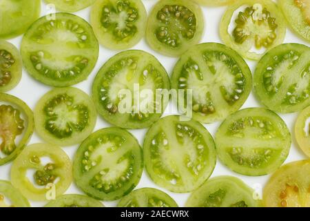 Pomodori verdi a fette su sfondo bianco. Modello. Natura morta Foto Stock