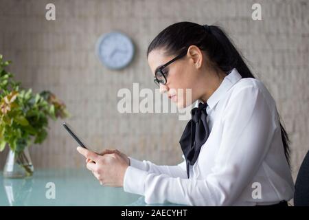 Donna intelligente con tavoletta digitale in ufficio, vista di profilo Foto Stock