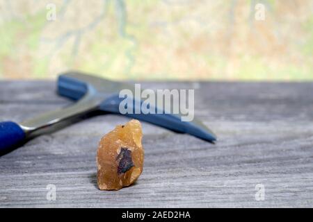 Il geologo del martello minerale e sono disposti su una tavola di legno contro una cartina topografica. Sfondo. Foto Stock