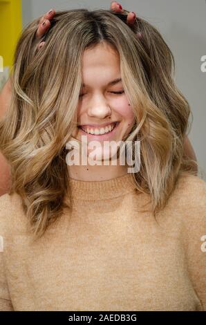 Ritratto di caucasici bella donna sorridente dopo la colorazione dei capelli. Parrucchiere mette le dita nei modelli di capelli e rende la sua risata. AirTouch tecnica Foto Stock